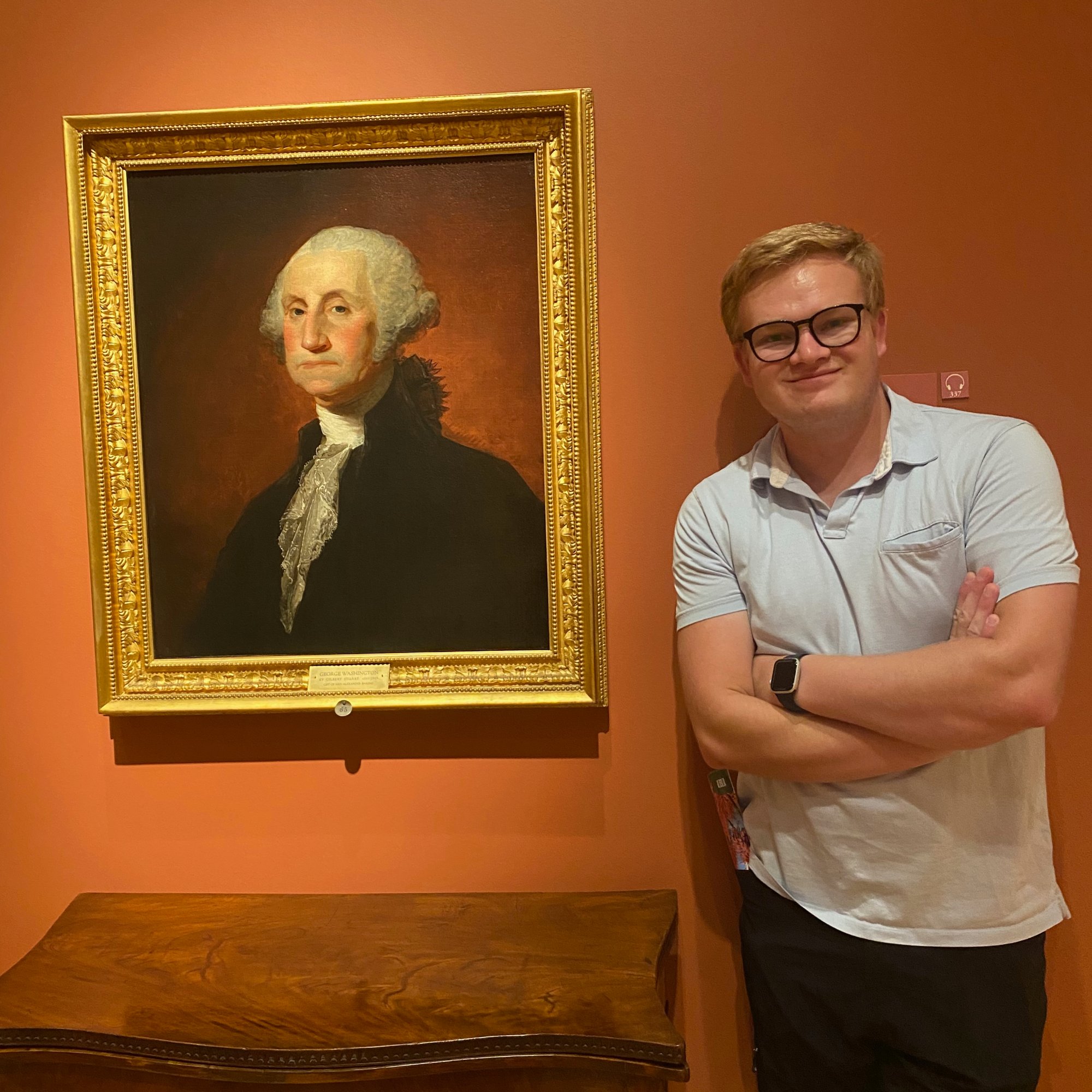 Grant standing next to a portrait of George Washington at a museum
